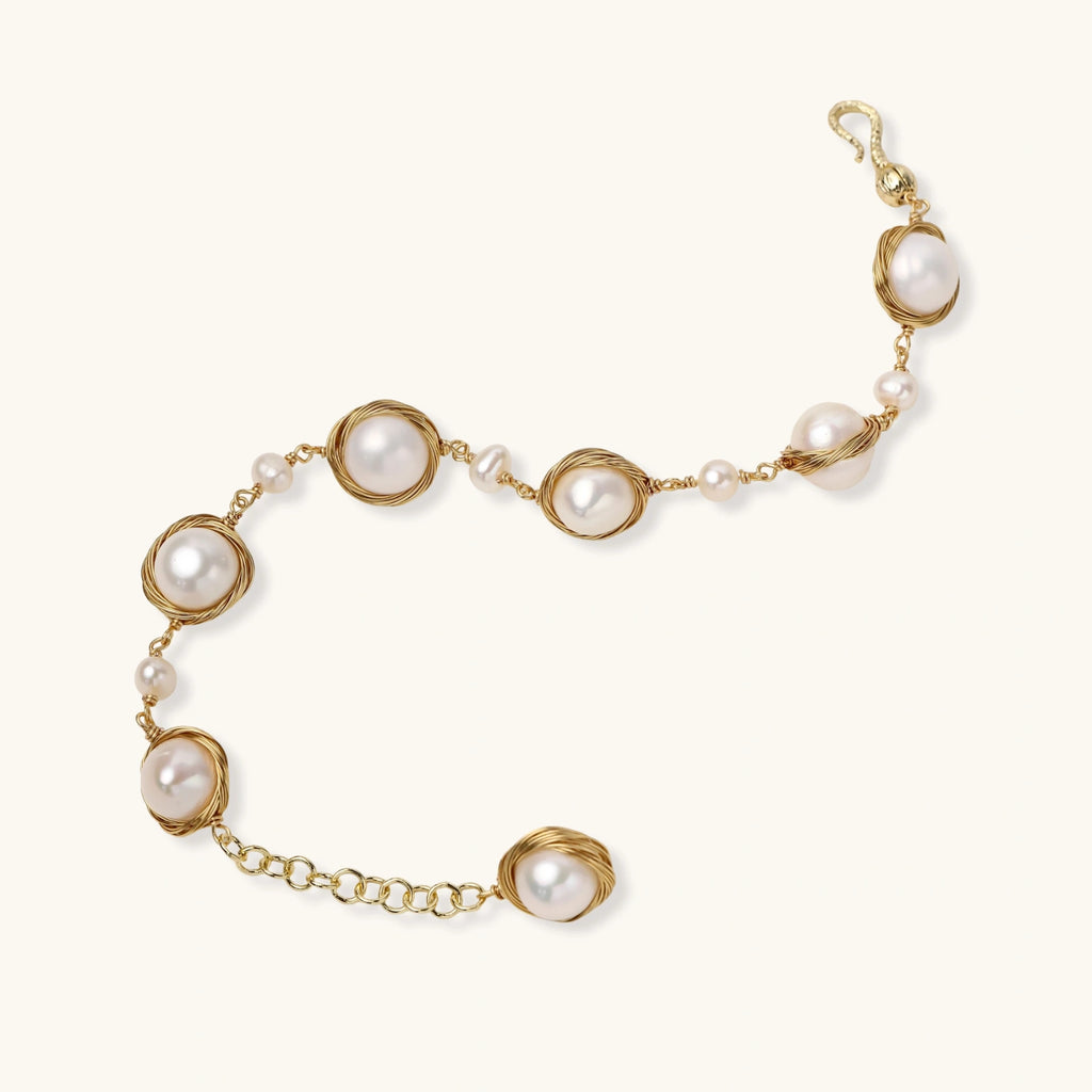Gold wire-wrapped freshwater pearl bracelet with alternating pearl sizes on cream background, adjustable length